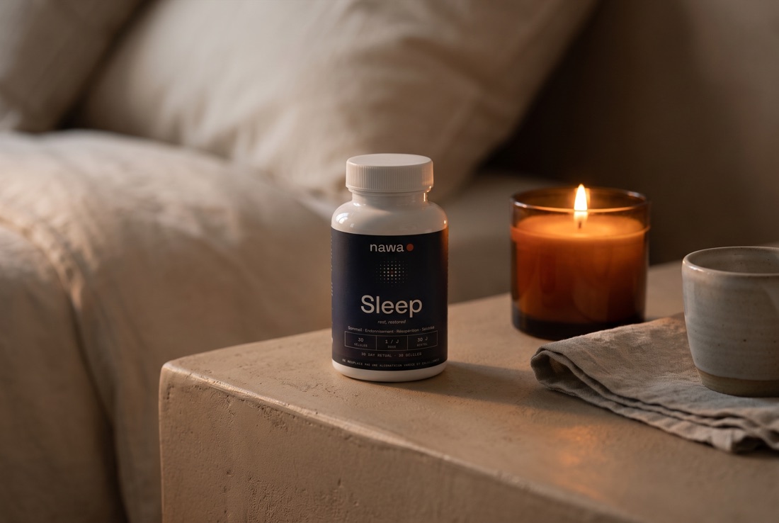 Flacon NAWA Sleep sur une table de chevet avec une bougie allumée